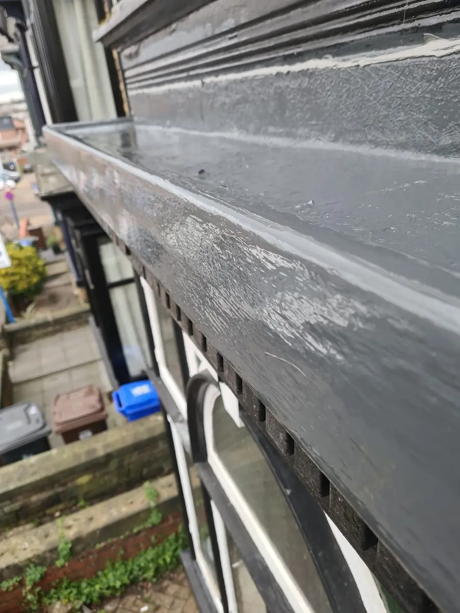 Freshly coated grey fibreglass bay window roof with a repainted black timber fascia and dentil moulding on a Newcastle terrace