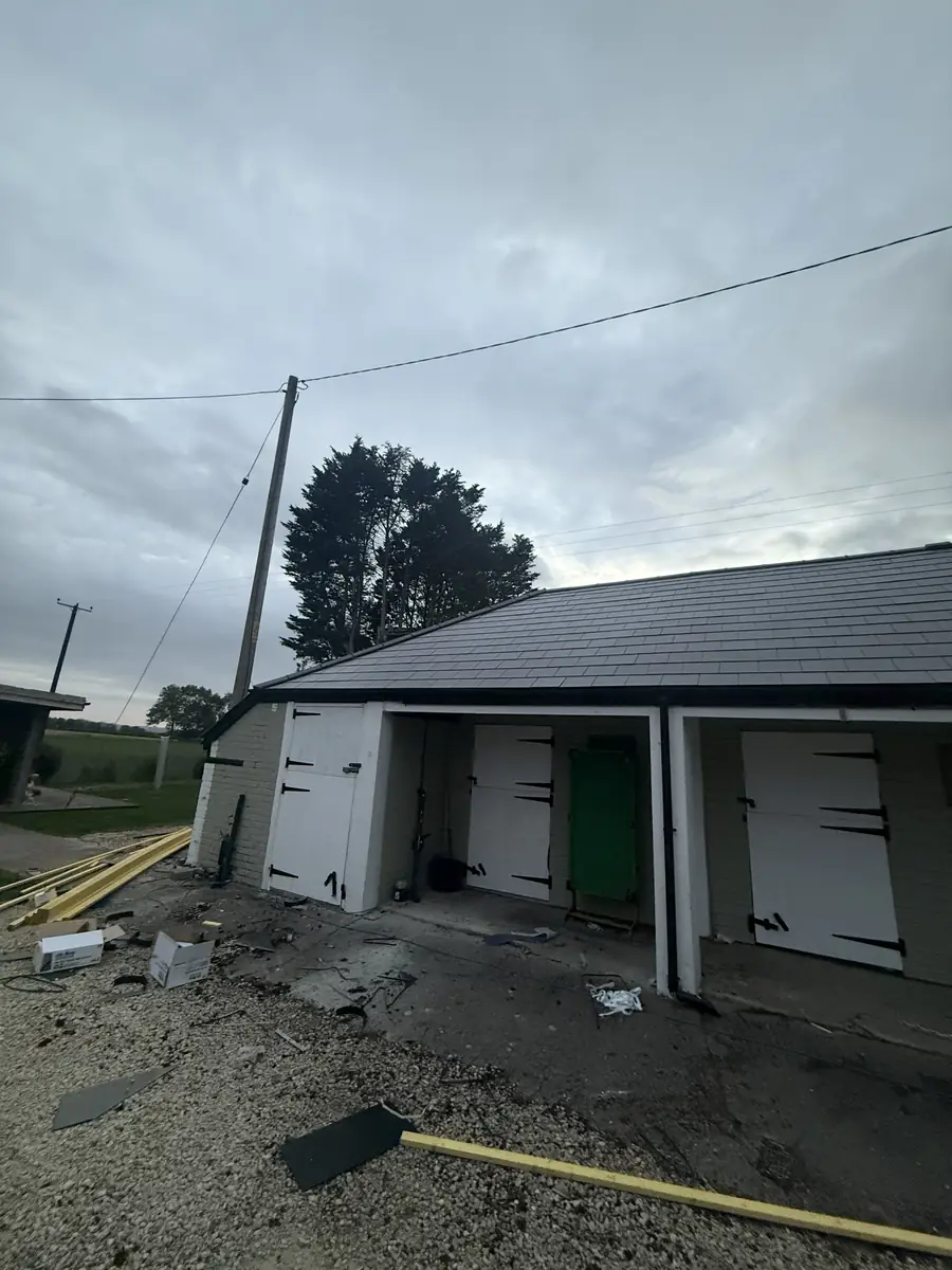 Row of garages with a new roof being fitted and the yard cleared of old materials