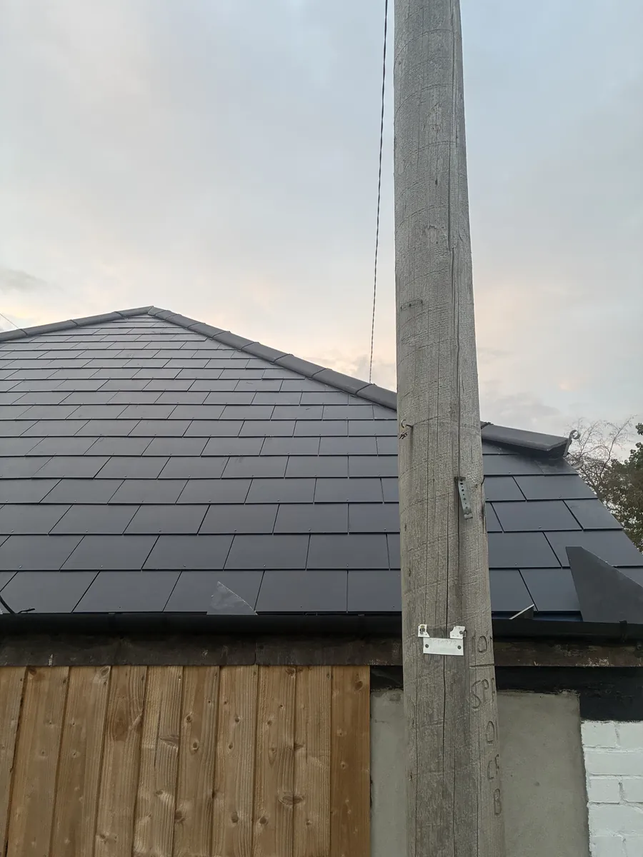 Newly slated outbuilding roof beside a timber fence with a telegraph pole in front