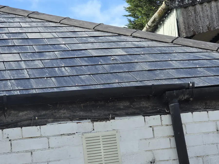 New slate roof with black fascia board and guttering on a white painted building